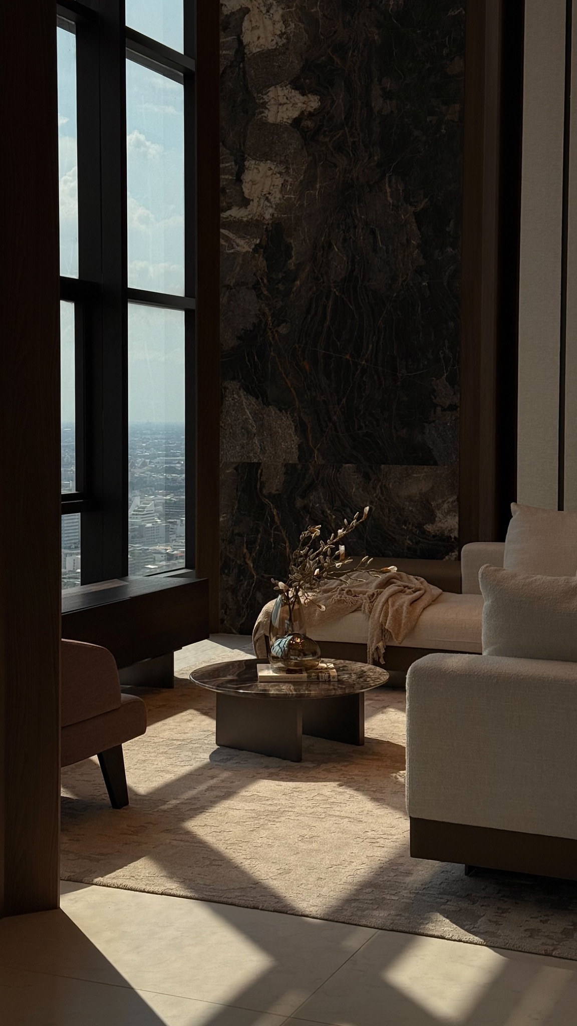 Sunlit city residence with a marble feature wall, cream seating and skyline views