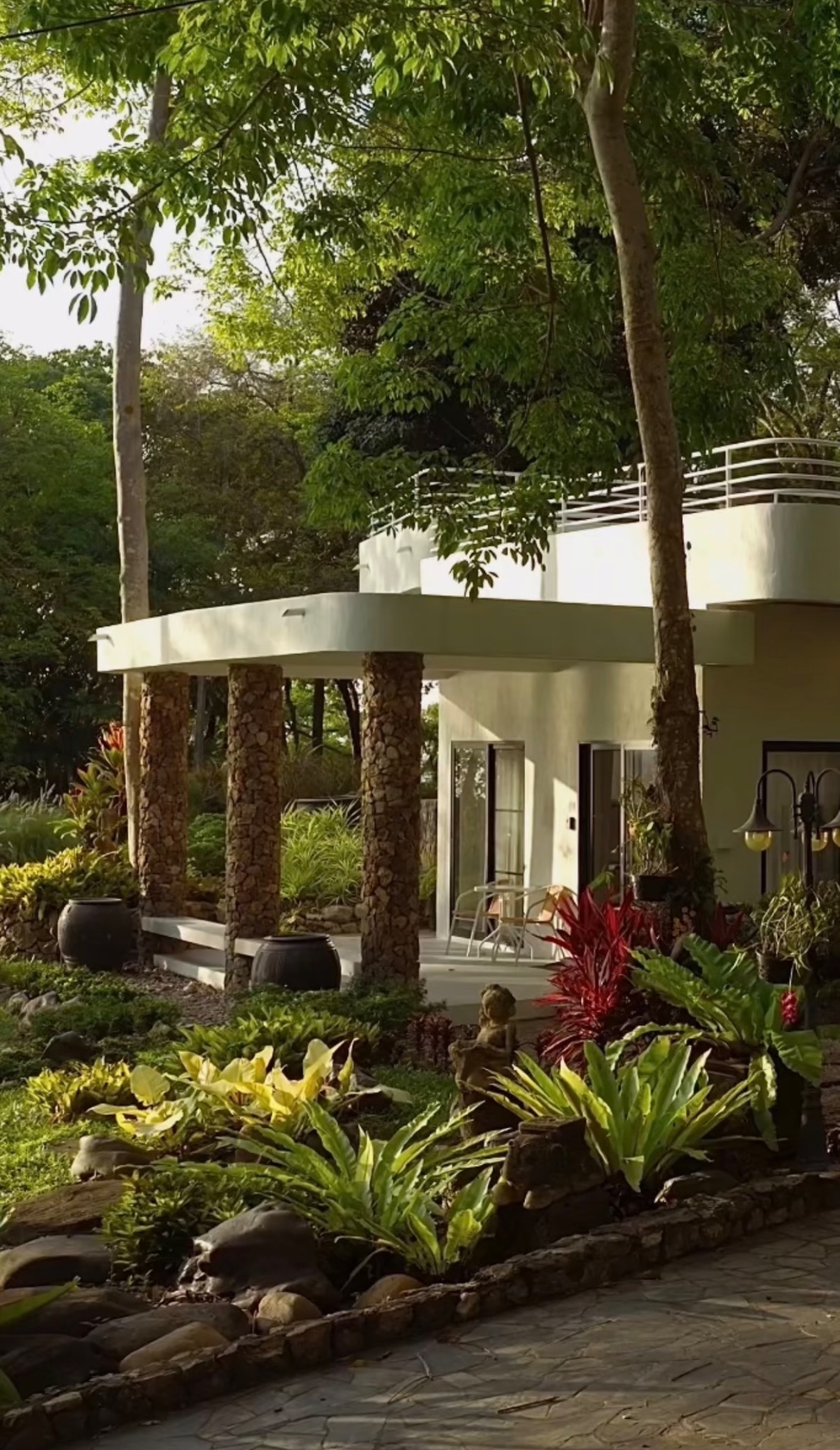 A private residence with stone columns surrounded by lush tropical gardens